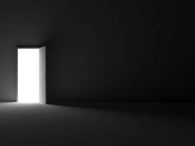Grayscale shot of an open door letting light into a dark room